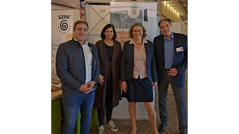 Vor GEPA-Bannern auf einem Messegelände steht Katrin Göring-Eckardt zusammen mit drei GEPA-Mitarbeiter*innen.