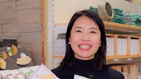 Portrait einer lächelnden Frau vor einem Regal mit Seifen. 