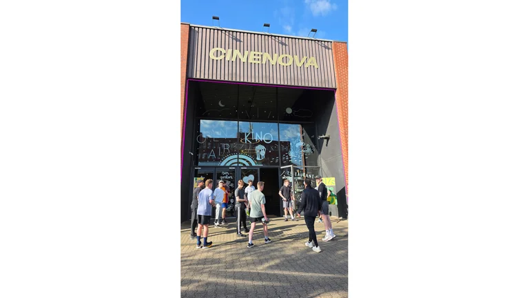 enschen in Sportkleidung gehen auf das Kino &ldquo;Cinenova&rdquo; zu. 