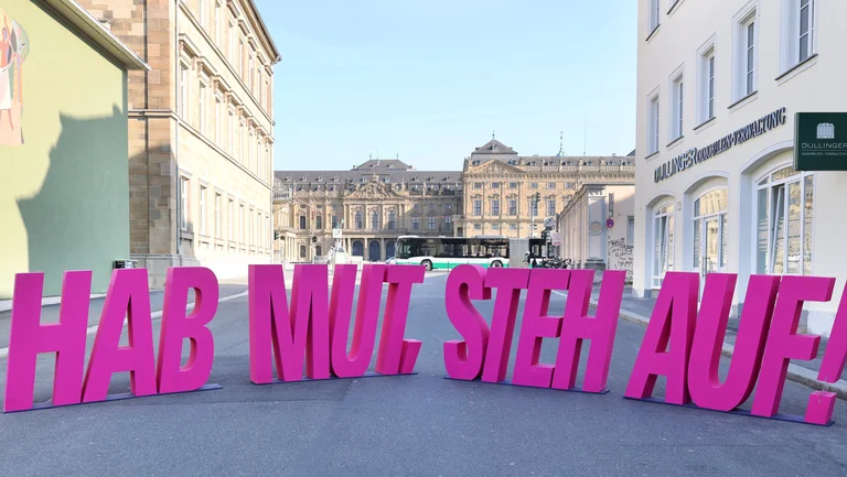 Die Buchstaben "HAB MUT, STEH AUF!" stehen menschengro&szlig; vor der Residenz in W&uuml;rzburg