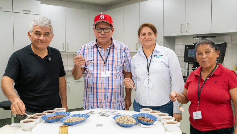 Gruppenfoto vier Personen im GEPA-Kaffeelabor halten Löffel mit Kaffee darauf in der Hand