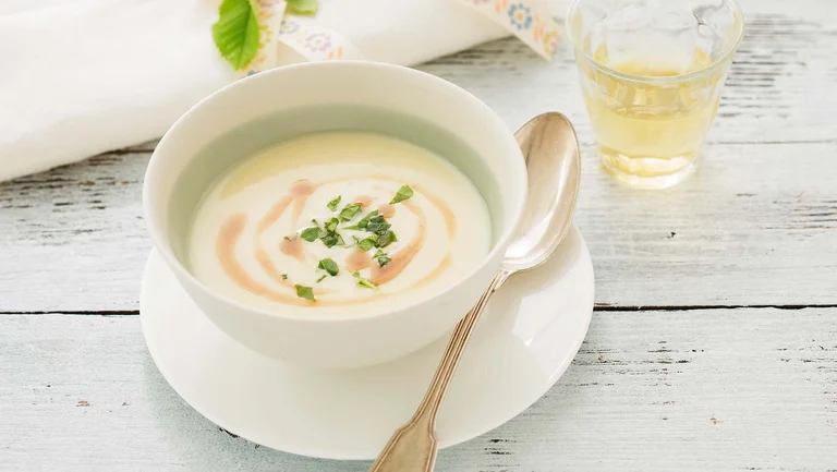 Helle Mairübchen-Suppe in einer weißen Suppenschüssel auf einem weißen Unterteller
