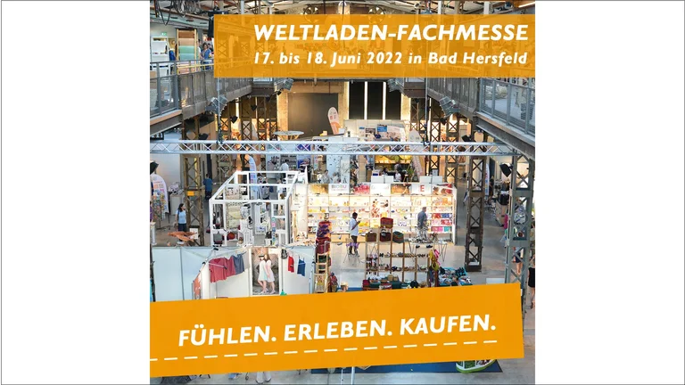 Blick von erhöhter Position auf das Innere einer Messehalle. Darüber sind die Texte "Weltladen-Fachmesse 17. bis 18. Juni 2022 in Bad Hersfeld" und "Fühlen. Erleben. Kaufen" eingeklinkt.