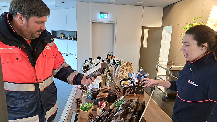 Sanitäter Kevin Frey begutachtet die fairen GEPA-Produkte im neu gestalteten Malteser-Café in Bietigheim-Bissingen. Rechts im Bild: Bezirksgeschäftsführerin Jessica Koch