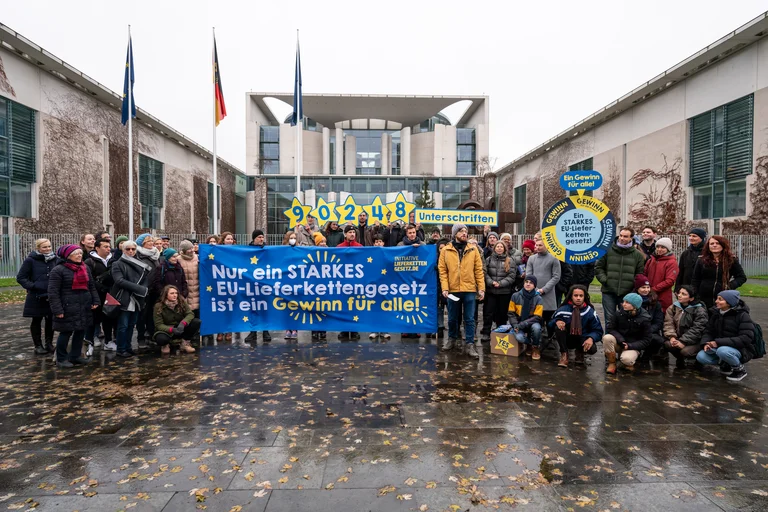 Gruppe von ca. 40 Demonstrierenden vor dem Kanzleramt in Berlin. Sie halten u.a. ein Banner mit "Nur ein starkes EU-Lieferkettengesetz ist ein Gewinn f&uuml;r alle!"