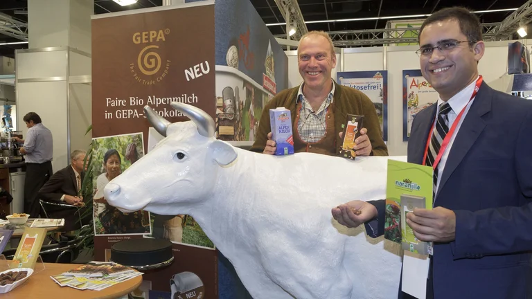 Zwei Männer mit einer weißen Kuh-Figur auf der Anuga 2011 in Köln