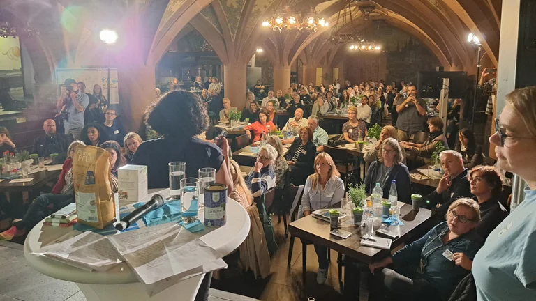 Blick von einer B&uuml;hne, die in einer Kirche steht, auf ein gut 50-k&ouml;pfiges Publikum