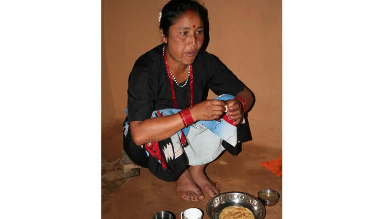 Bishnu Chhetri sitzt mit ihrer Mahlzeit auf dem Boden.