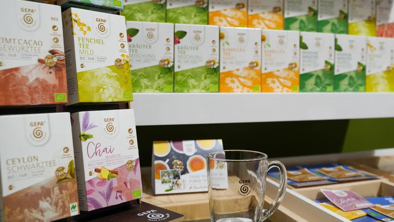 GEPA-Teebeutel im Display und im Regal, davor ein Teeglas.