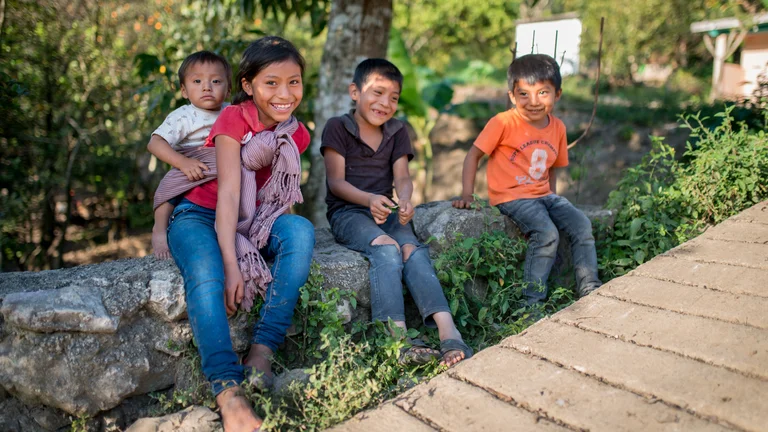 Lächelnde Kinder sitzen auf einem Stein auf einer Wiese
